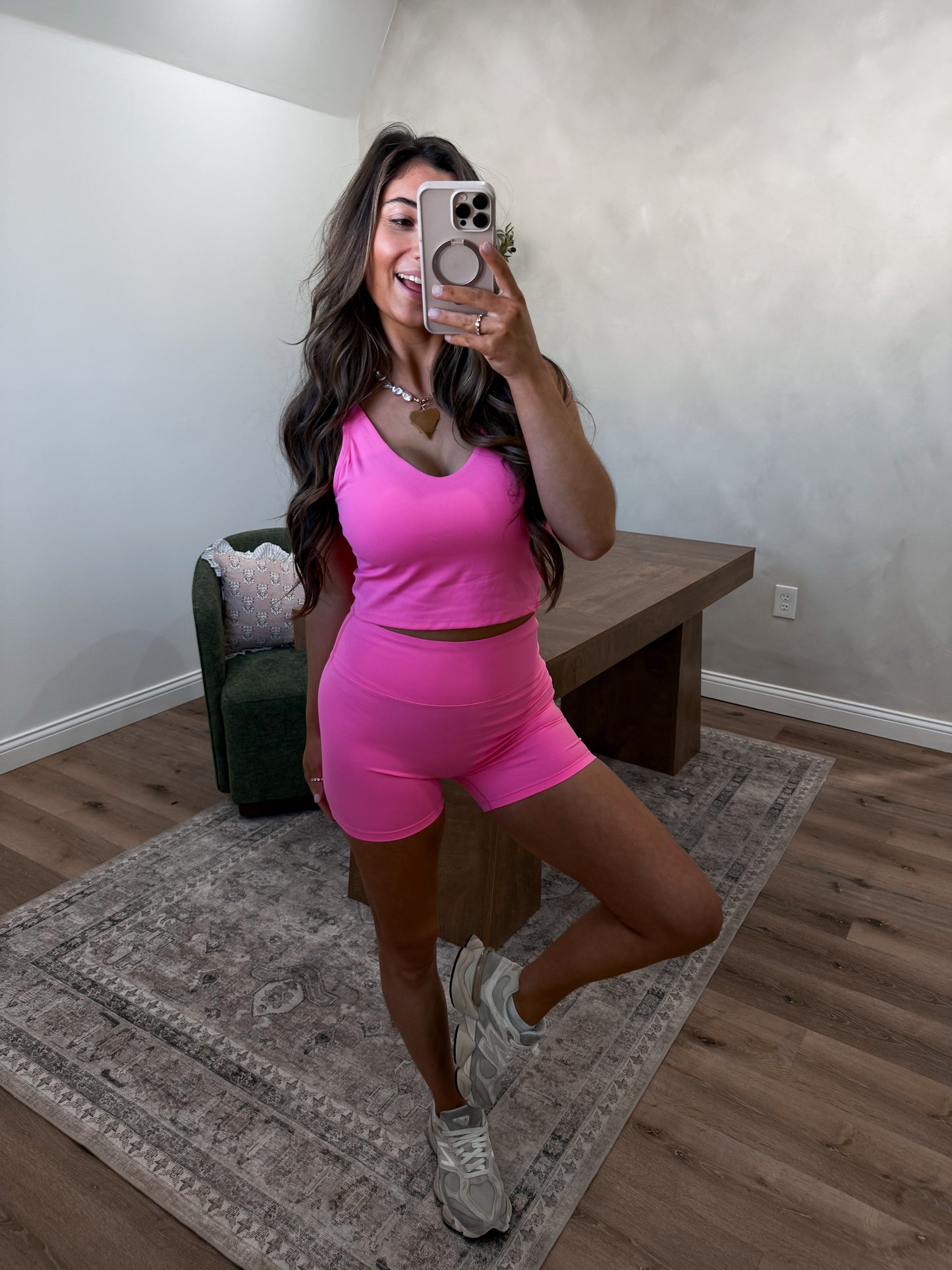 Woman taking a mirror selfie wearing a pink athletic outfit in a home setting.