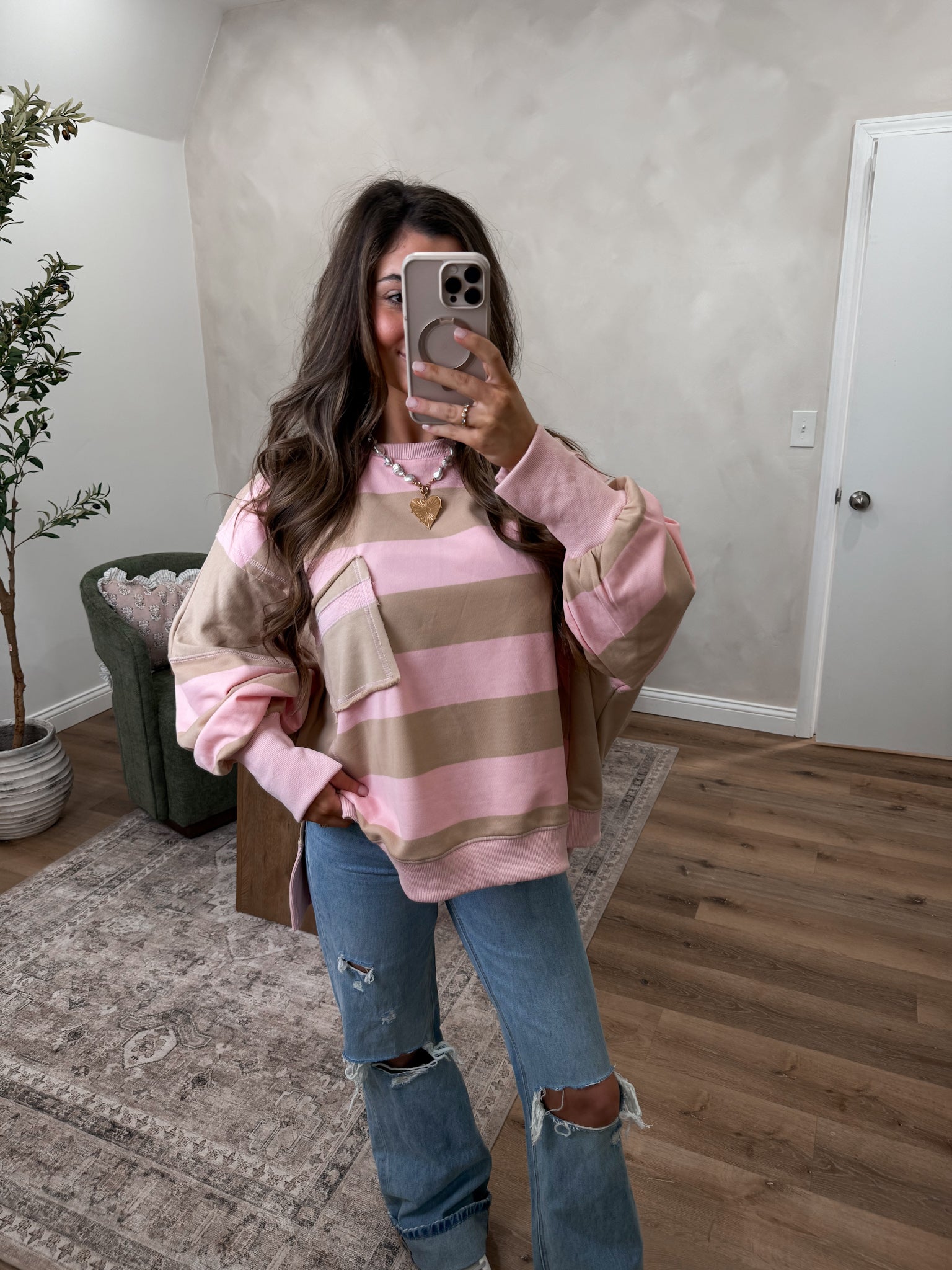 Person wearing a pink and brown striped sweater with a coat in a room.