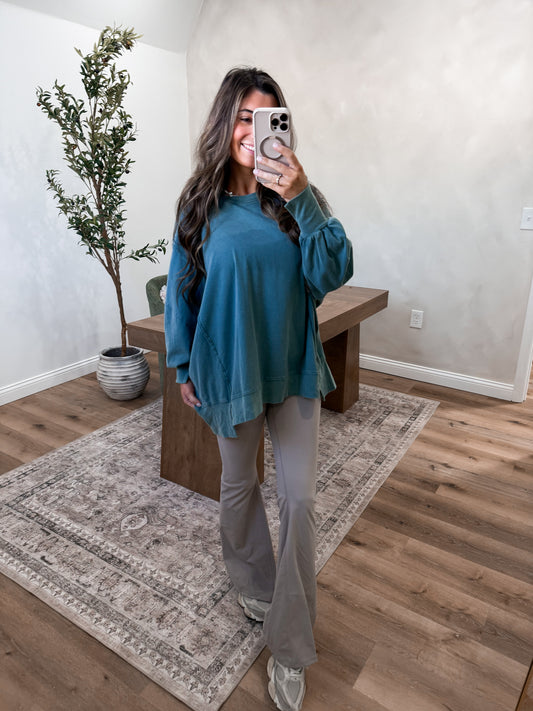 Woman taking a mirror selfie in a room with wooden flooring and a plant.