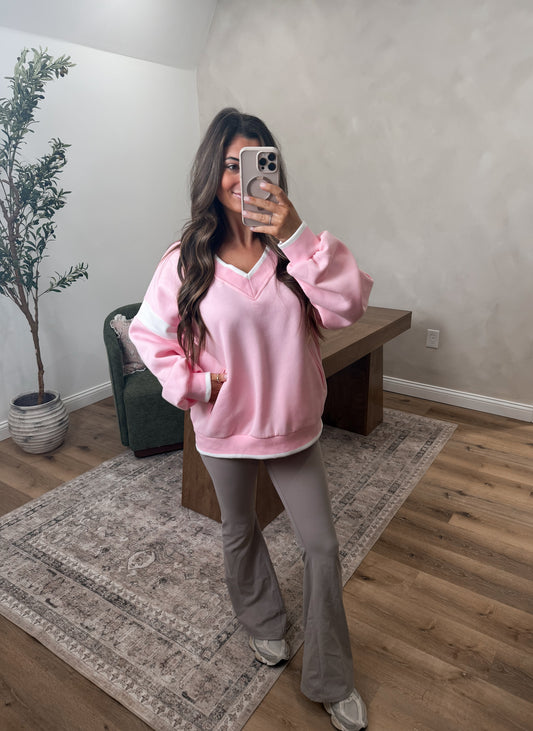 Women modeling a pink variety style pullover in a room 