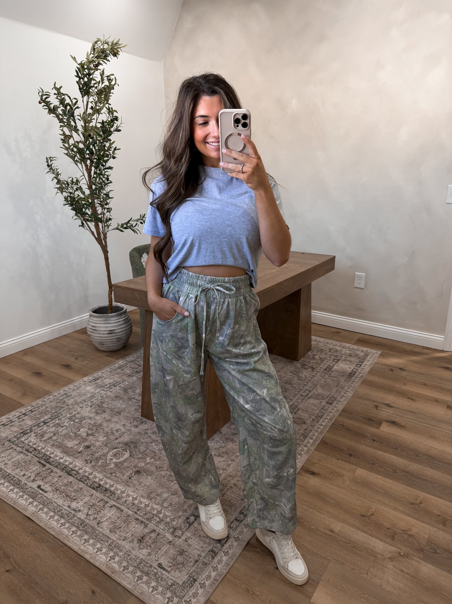 Camo jogger pants on a model in a room 