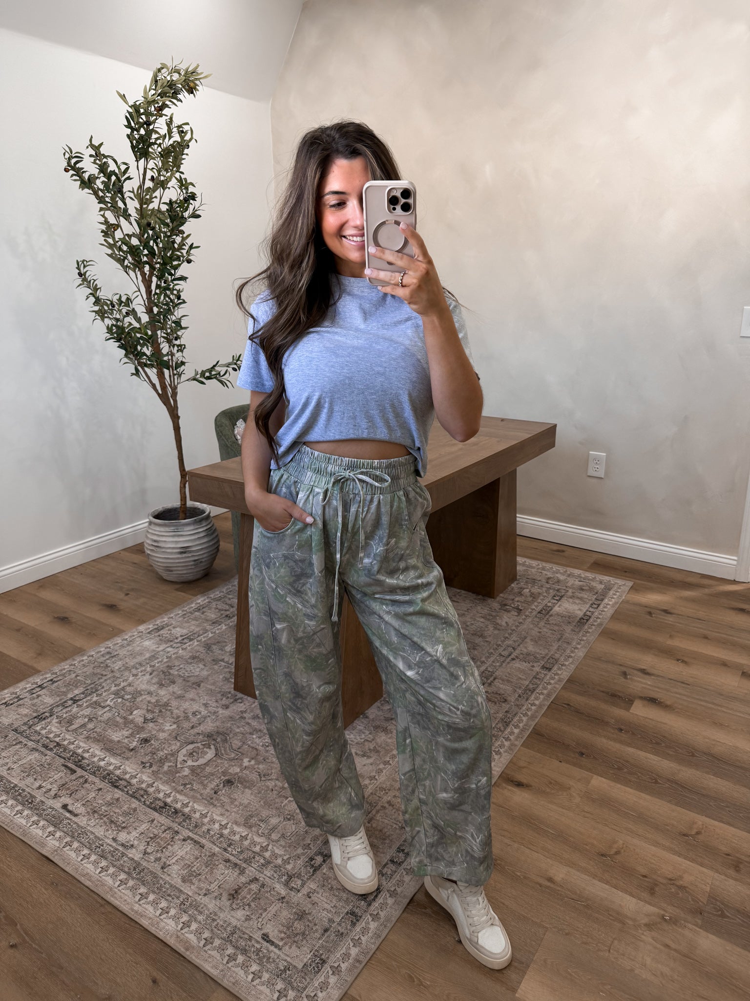 Camo jogger pants on a model in a room 