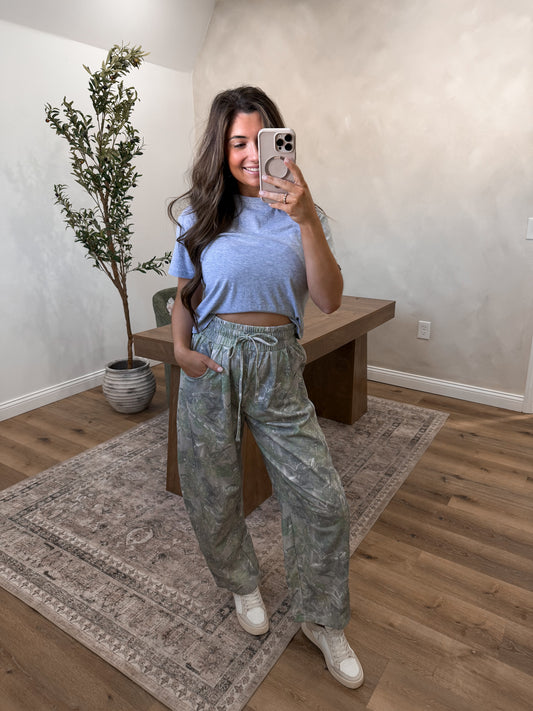 Camo jogger pants on a model in a room 
