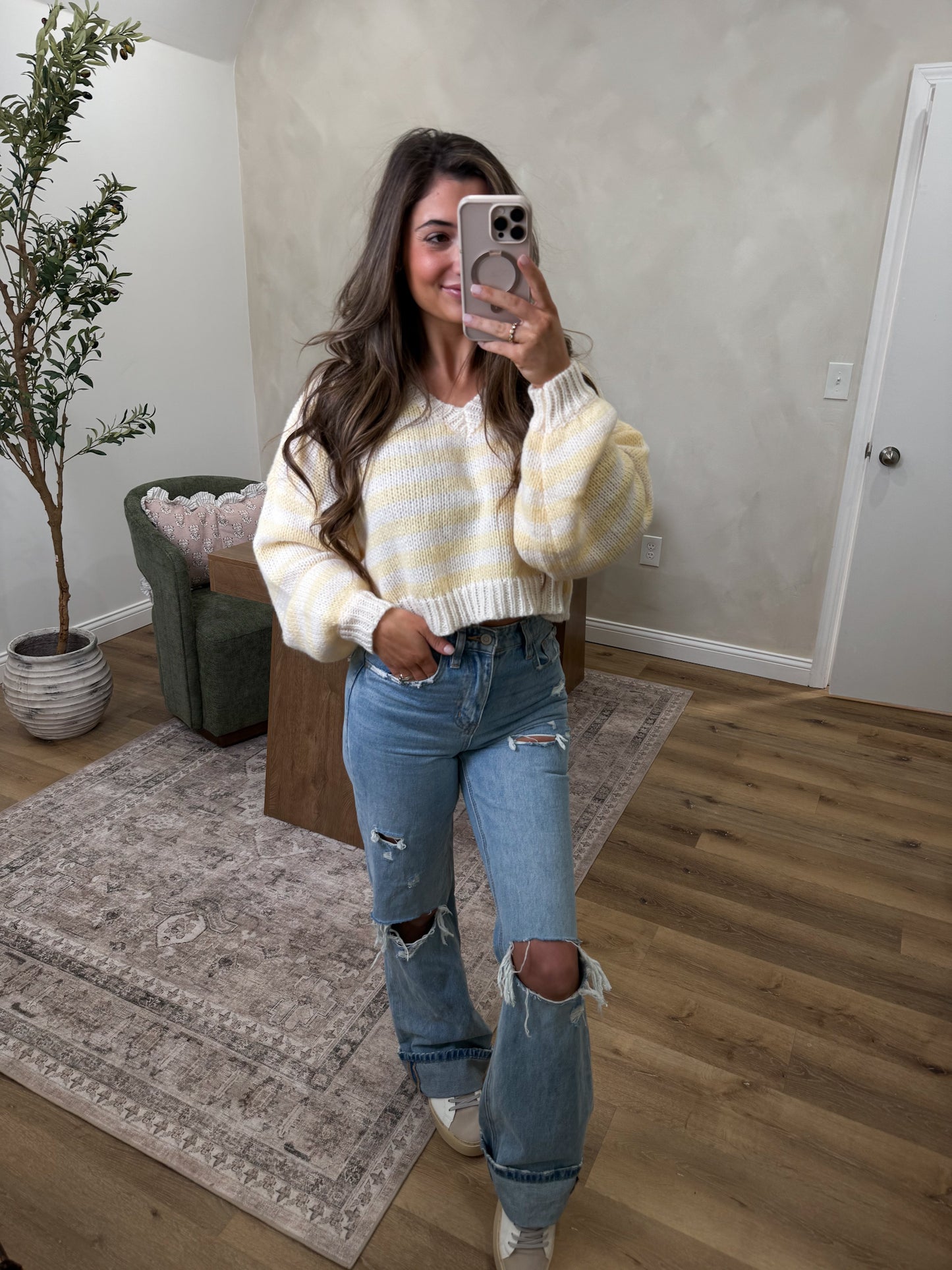 Women wearing jeans and a yellow striped sweater 