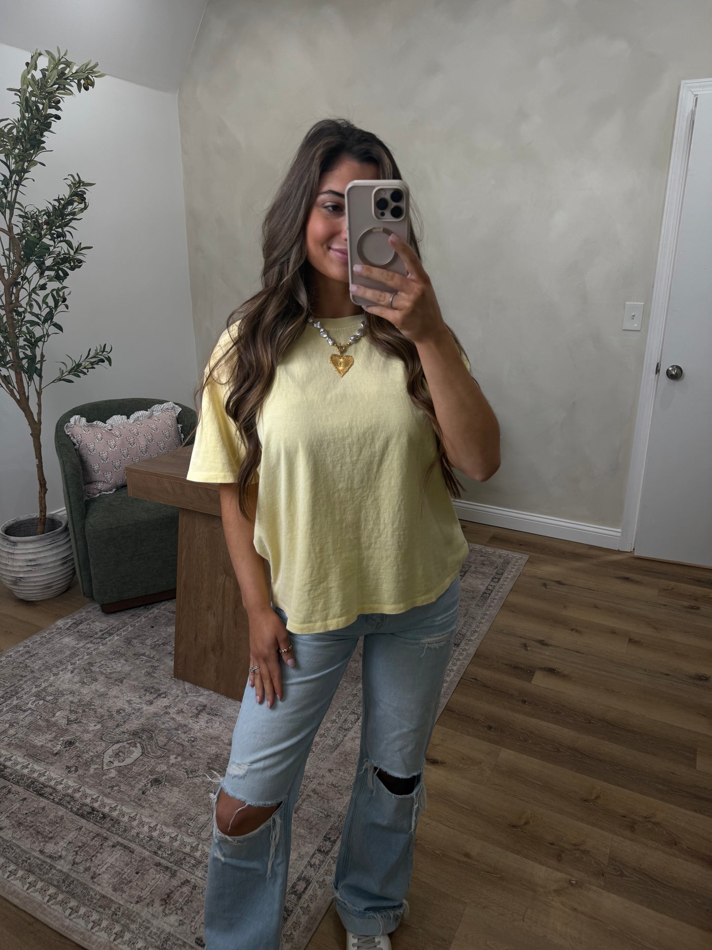 Person taking a mirror selfie wearing a yellow top and blue jeans in a room. Full length cotton tee shirt 